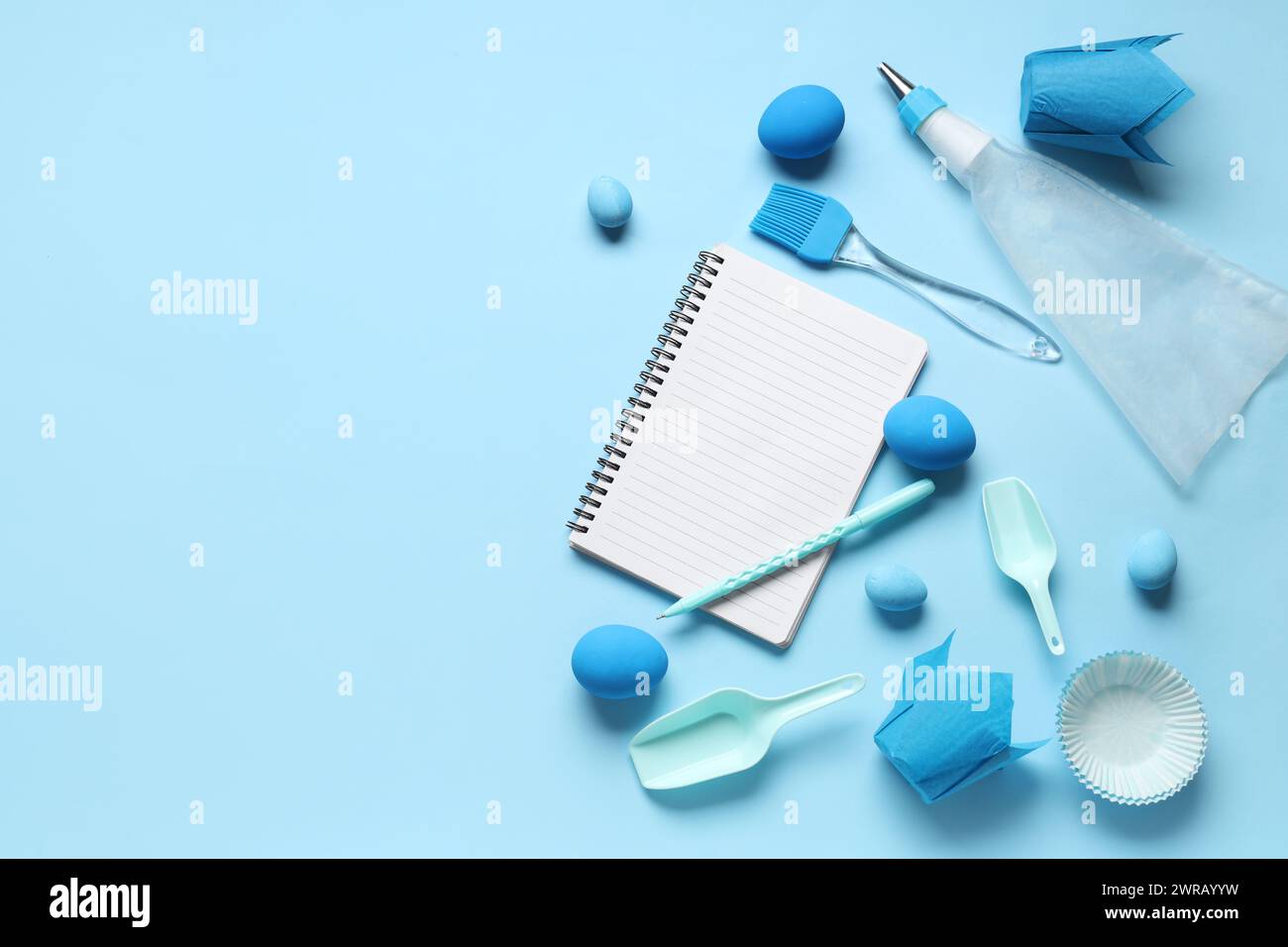 Blank notepad for recipes with pen, baking tools and Easter eggs on blue background Stock Photo