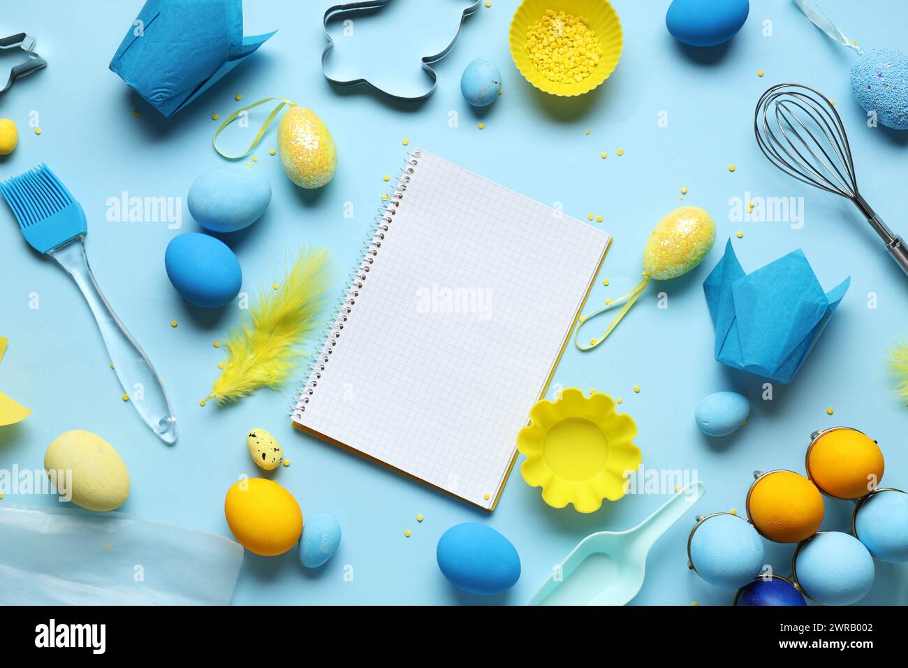 Blank notepad for recipes with baking tools and Easter eggs on blue background Stock Photo