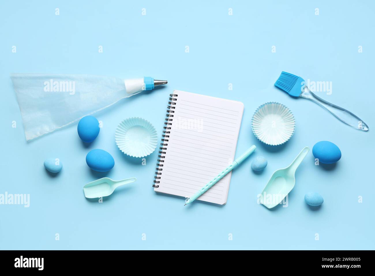 Blank notepad for recipes with pen, baking tools and Easter eggs on blue background Stock Photo