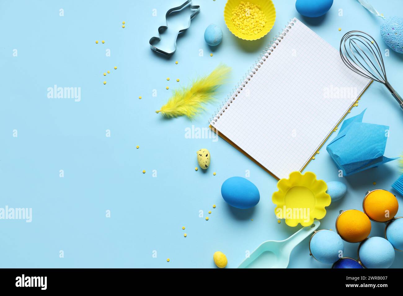 Blank notepad for recipes with baking tools and Easter eggs on blue background Stock Photo