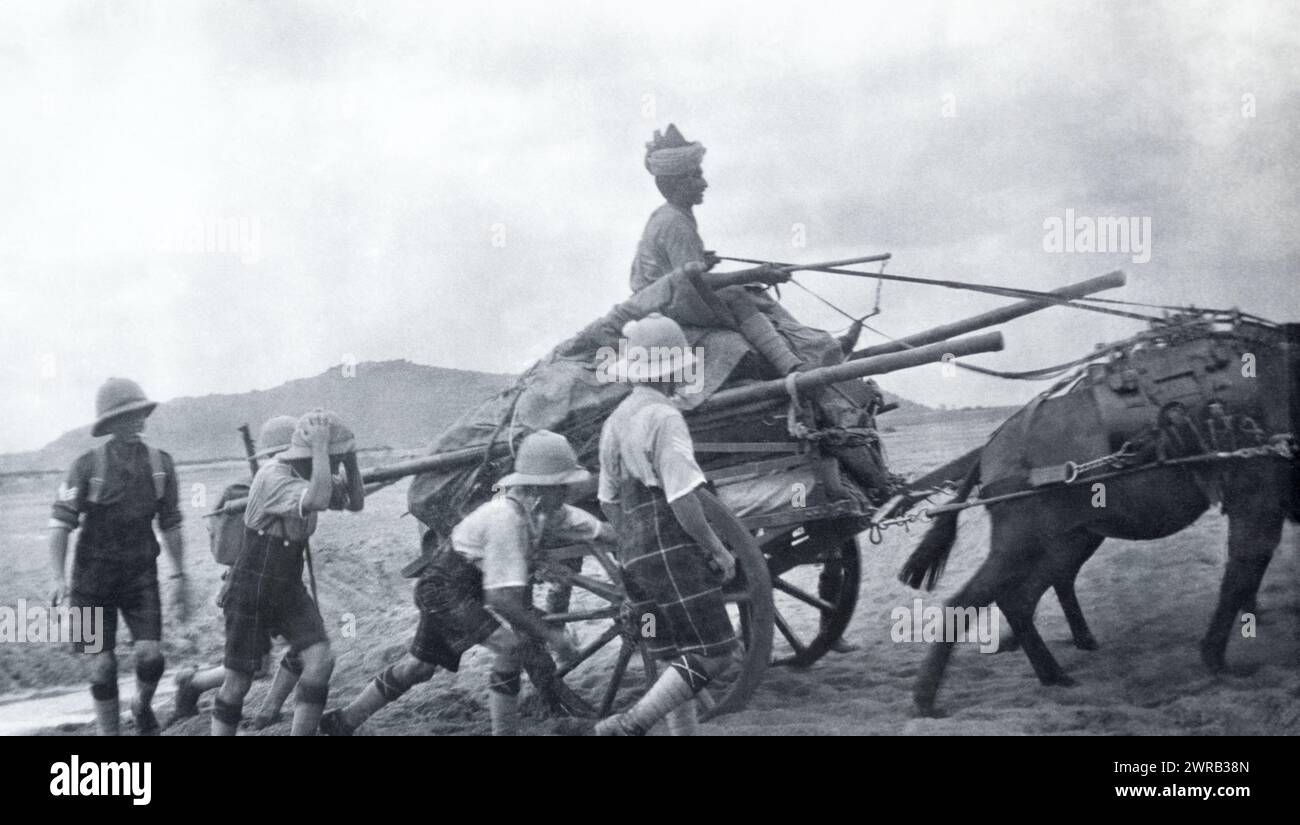 Soldiers of the 2nd Battalion Highland Light Infantry pushing a cart uphill in British India, c. 1925. Stock Photo