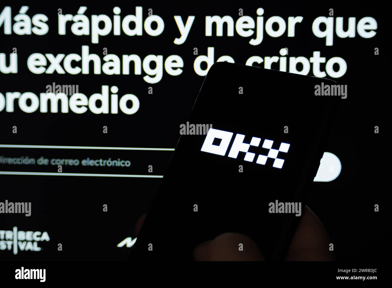 Cordoba Province, Argentina - March 11, 2024: OKX application opening on a cell phone. In the background you can see the official OKX page. Stock Photo