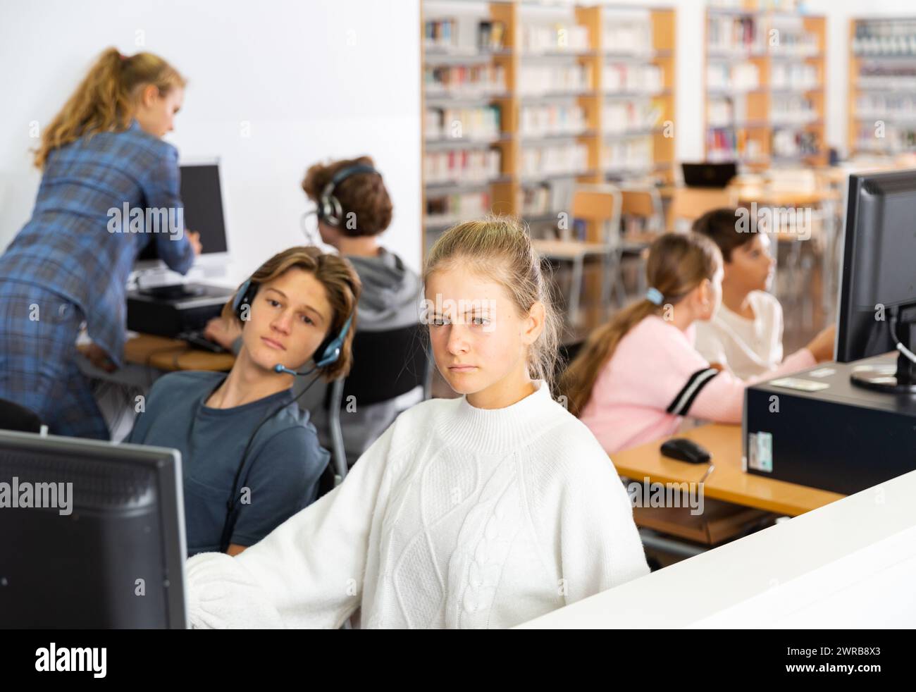 Pupils using computers at lesson, teacher teaching them in class room ...