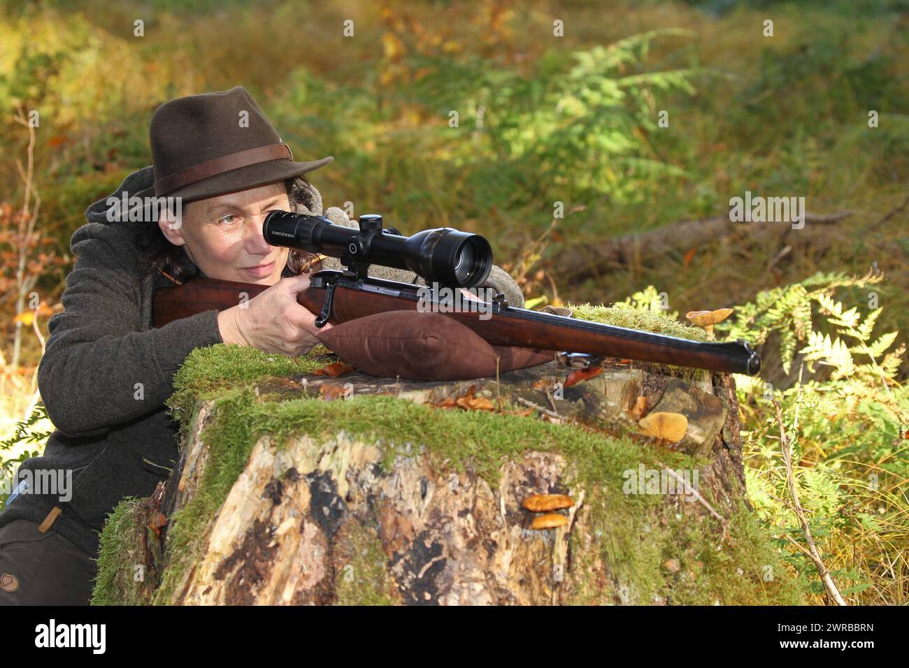 Huntress aims rifle with telescopic sight, Allgaeu, Bavaria, Germany Stock Photo