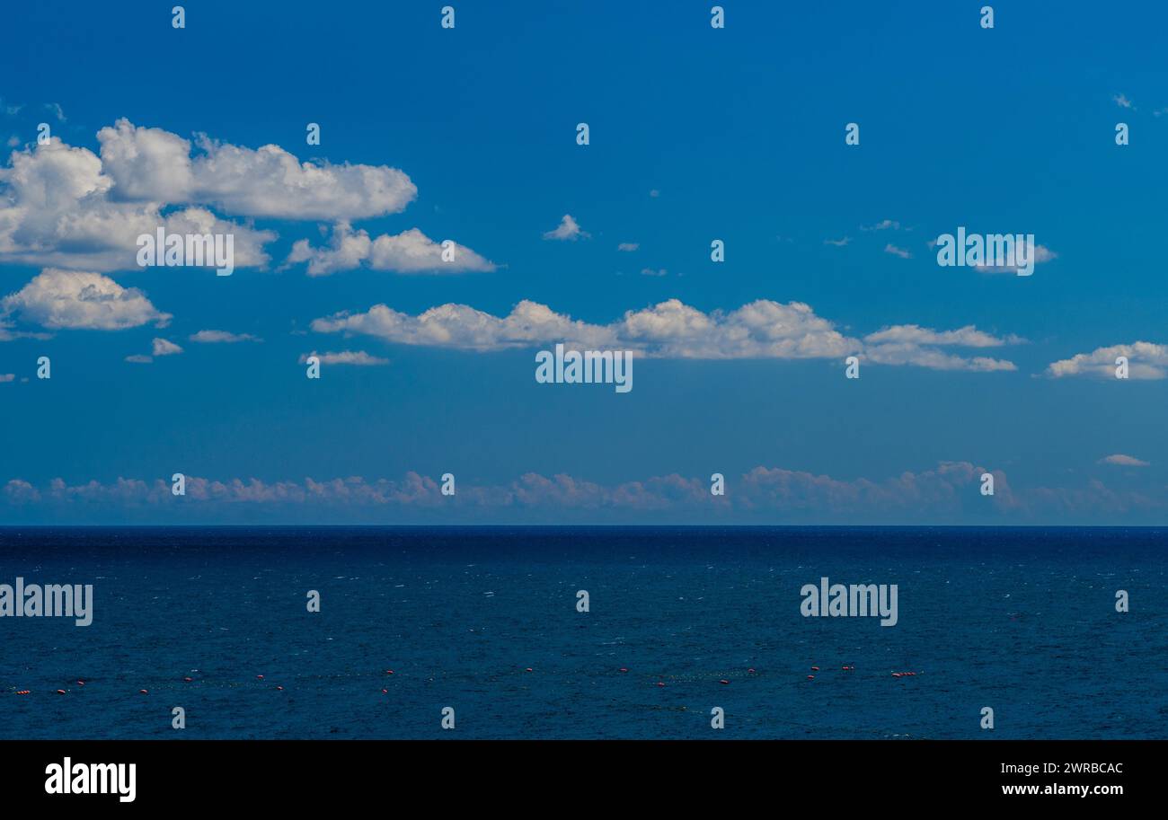 Expansive view of the ocean beneath a clear blue sky with fluffy clouds ...