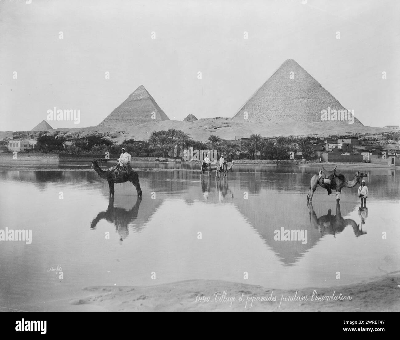 Egypt. Village and pyramids during the flood-time. ca. 189-, Photo shows men on camels and one man standing next to a camel in shallow flood water, with pyramids in the background, in Egypt., Carpenter, Frank G. (Frank George), 1855-1924, collector, between 1890 and 1900, Pyramids, Egypt, 1890-1900, Photographic prints, 1890-1900., Photographic prints, 1890-1900, 1 photographic print Stock Photo