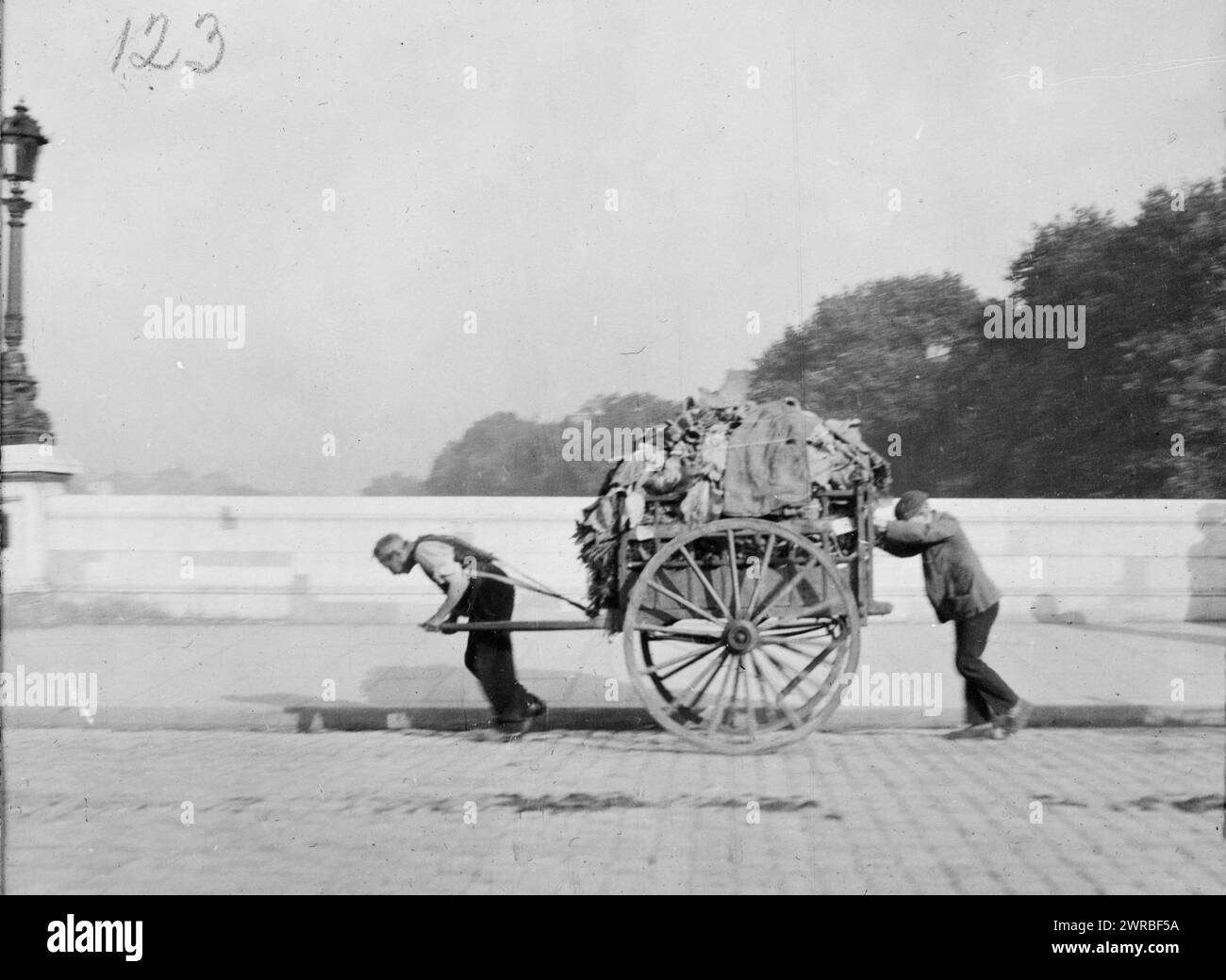 Paris, France, ca. 1920, Photo shows an elderly man pulling and a young man pushing a large two-wheel cart loaded with rags on a cobblestone street in Paris, France., Carpenter, Frank G. (Frank George), 1855-1924, collector, ca. 1920, Ragpicking, France, Paris, 1920, Photographic prints, 1920., Photographic prints, 1920, 1 photographic print Stock Photo