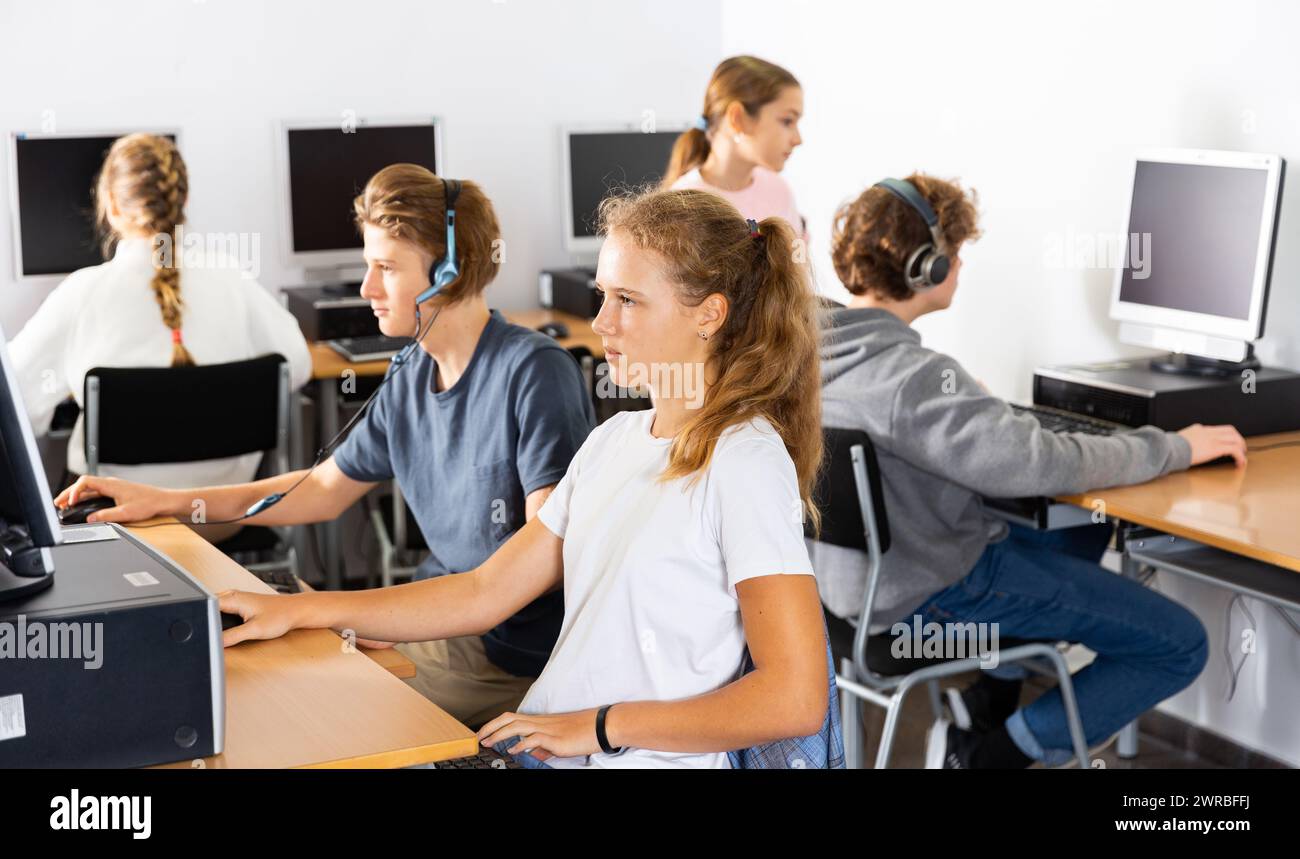 Pupils using computers at lesson, teacher teaching them in class room ...