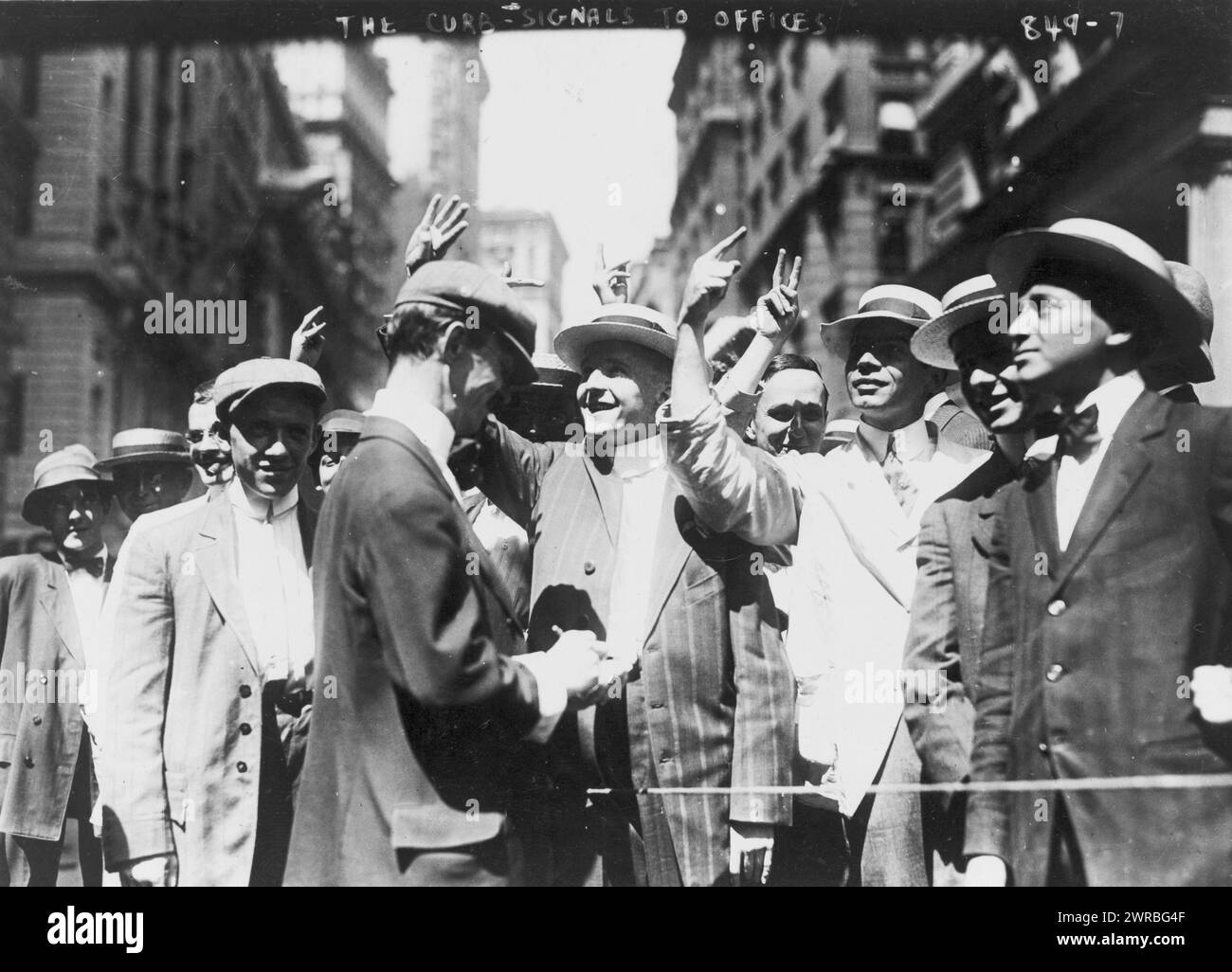 Signalling to offices, curb market, New York City, Stock trading on the New York Curb Association market, with brokers and clients signalling from street to offices., c1916., Stock exchanges, New York (State), New York, 1910-1920, Photographic prints, 1910-1920., Photographic prints, 1910-1920, 1 photographic print Stock Photo