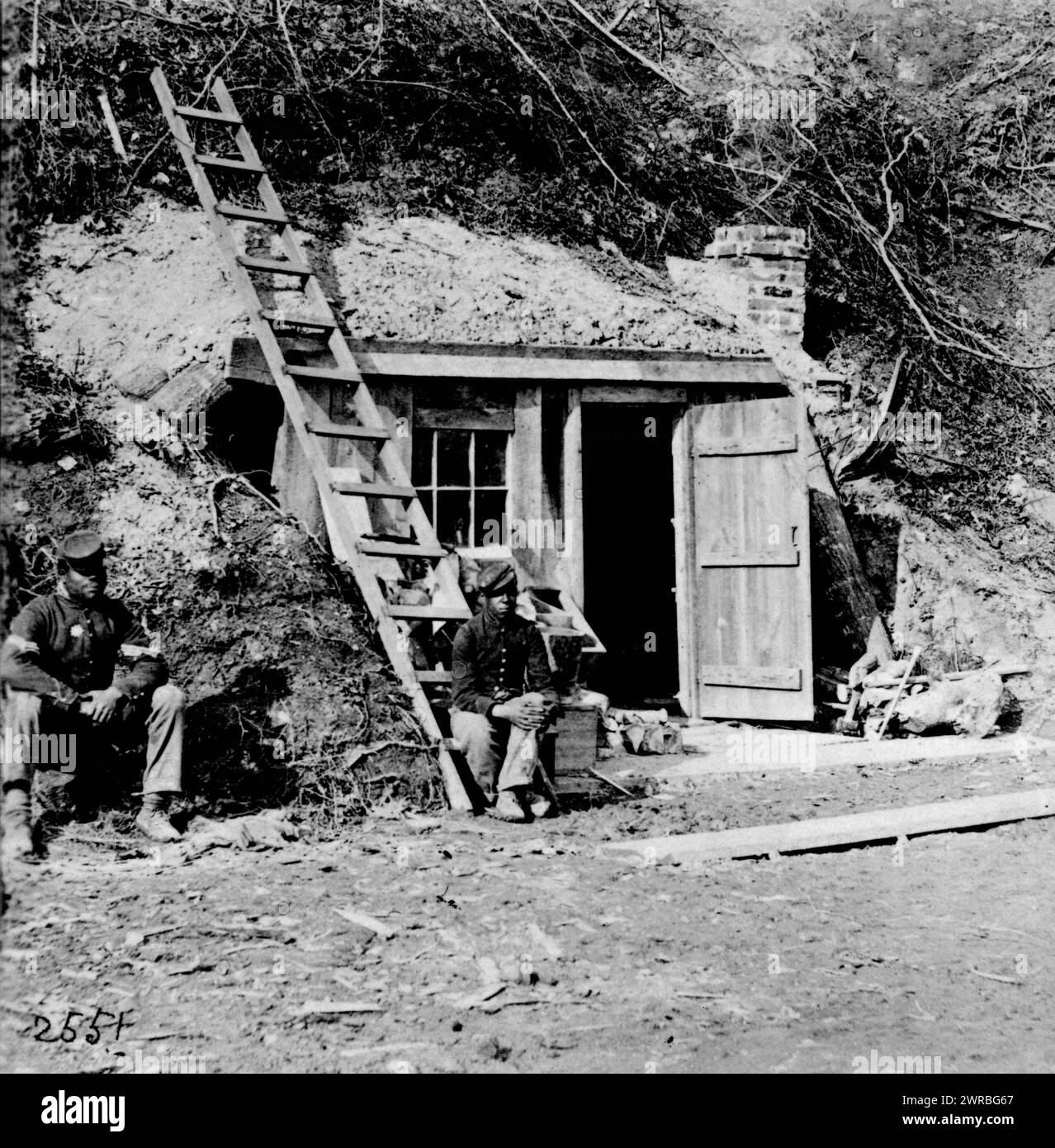 Dutch Gap Canal ... November 1864, while Canal was being dug, Two African American soldiers seated in front of small building in bottom of cliff, near Dutch Gap Canal., photographed 1864, printed later, African Americans, Military service, Virginia, 1860-1870, Photographic prints, 1860-1910., Photographic prints, 1860-1910, 1 photographic print Stock Photo