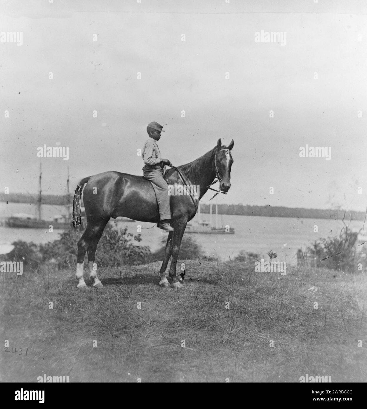 African American boy seated on a horse near a river, Photograph incorrectly captioned as being taken at Cold Harbor, Virginia, which is not located near a significant river, If the rest of the caption is correct, the boy is seated on General John A. Rawlins' horse on June 14, 1864, which means that the photograph was probably taken near the James River, possibly by a photographer associated with Mathew Brady, 1864 June 14, printed later., Rawlins, John A., (John Aaron), 1831-1869, Associated objects, Gelatin silver prints, 1860-1870., Gelatin silver prints, 1860-1870 Stock Photo