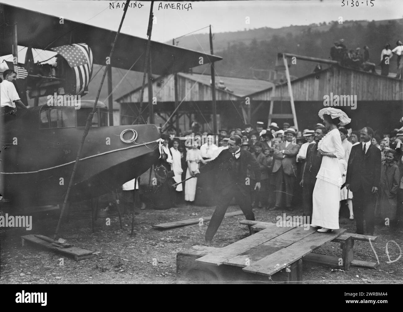 Naming 'America', Photograph shows the christening and launch of the Curtiss Model H Flying Boat airplane 'America' on June 22, 1914 in Hammondsport, New York. Aviator John Cyril Porte is using a sledgehammer to smash the champagne bottle as Katherine Masson and builder Glenn Curtiss (standing behind Masson) look on., 1914 June 22, Glass negatives, 1 negative: glass Stock Photo