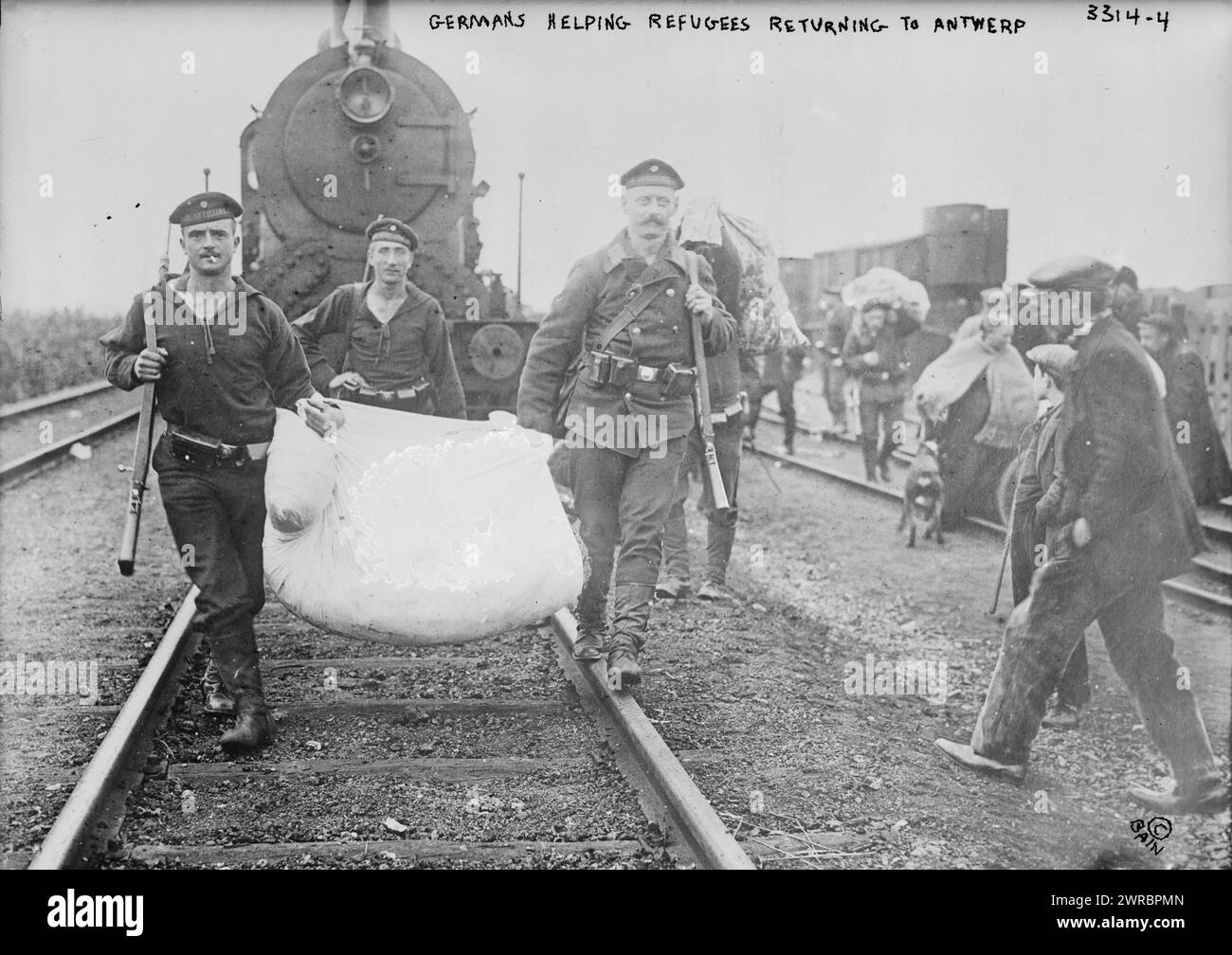 Germans helping refugees returning to Antwerp, Photograph shows German soldiers on train tracks carrying bundle for Belgian refugees in Antwerp, Belgium during World War I., 1914, World War, 1914-1918, Glass negatives, 1 negative: glass Stock Photo