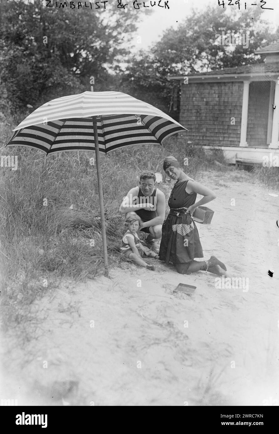 Zimbalist & Gluck, Photograph shows Romanian-born American soprano opera singer Alma Gluck (1884-1939) with her husband, Efrem Zimbalist, Sr. and their daughter Maria, under a beach umbrella, vacationing possibly on Fishers Island, New York, August, 1917. Zimbalist was an internationally known concert violinist, composer, teacher, conductor, and director of the Curtis Institute of Music., 1917 August, Glass negatives, 1 negative: glass Stock Photo