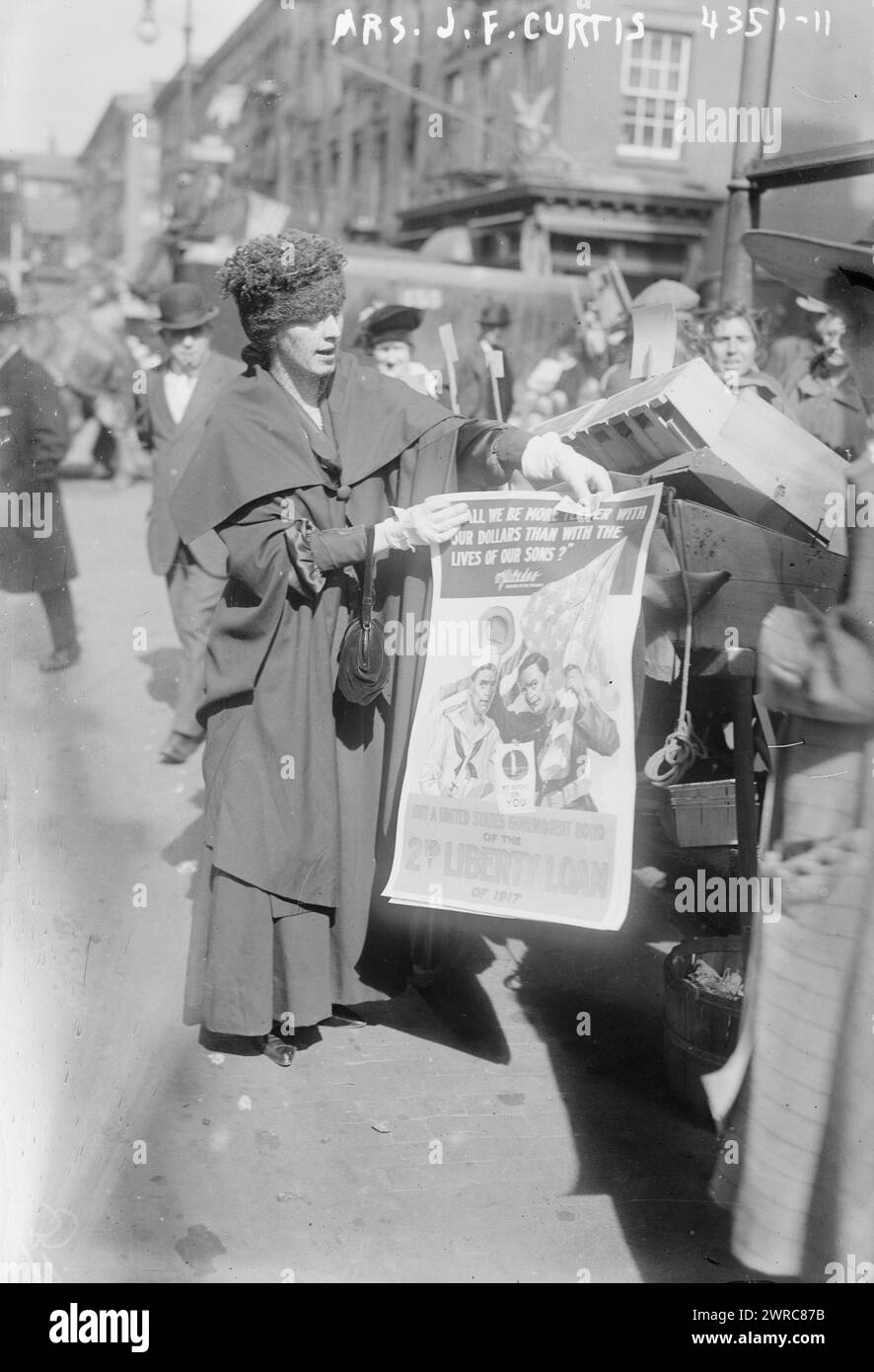 Mrs. J.F. Curtis, Photograph shows Mrs. James F. Curtis, (the former Laura Beatrice Merriam) wife of James F. Curtis, an Assistant Secretary at the Treasury Department; holding a poster for the 2nd Liberty Loan of 1917 during World War I. Behind her to the right is an Italian American woman who had three sons fighting in Europe., 1917 October, World War, 1914-1918, Glass negatives, 1 negative: glass Stock Photo