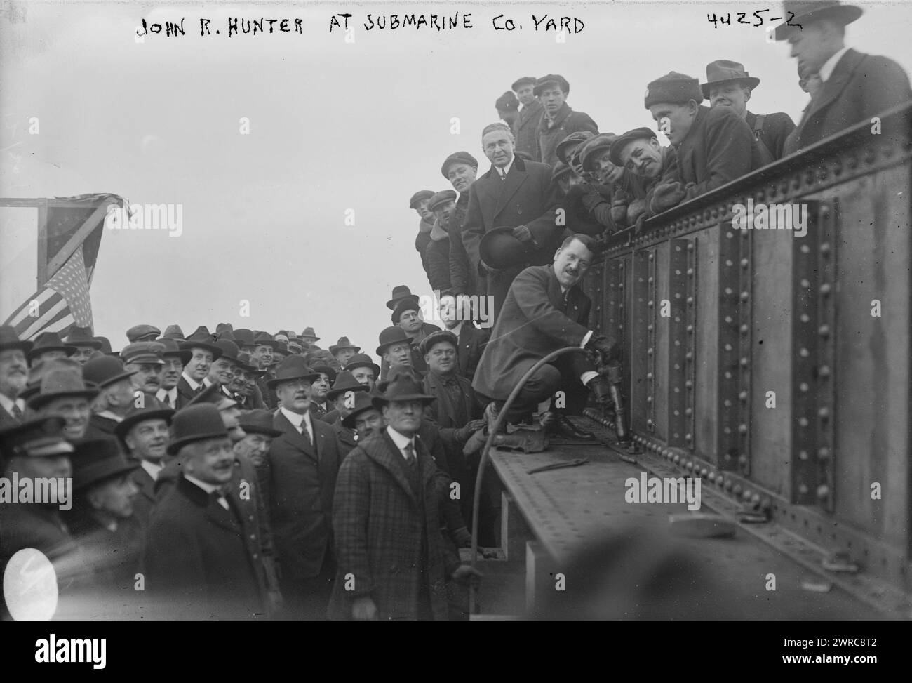 John R. Hunter at submarine Co. Yard, Photograph shows Mr. John Hunter of the United States Shipping Board, driving a rivet with Mr. Henry R. Sutphen, vice president of the Submarine Boat Corporation standing behind him at the Newark Bay Shipyard, Kearny, New Jersey. The men were attending a ceremony on December 20, 1917 marking the first rivet driven into 'the first standardized structural steel ship ever built.', 1917 Dec. 20, Glass negatives, 1 negative: glass Stock Photo