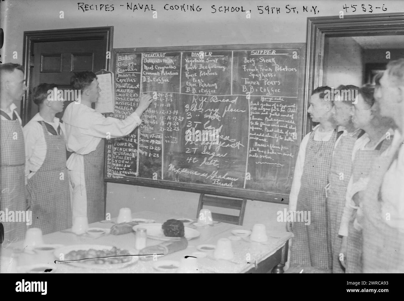 Recipes, Naval cooking school, 59th St. N.Y., Photograph shows students looking at a blackboard on which are written recipes for rye bread and other foods, at the New York Cooking School, 126 East 59th Street, which trained soldiers to cook for the Navy during World War I., between ca. 1915 and 1918, World War, 1914-1918, Glass negatives, 1 negative: glass Stock Photo