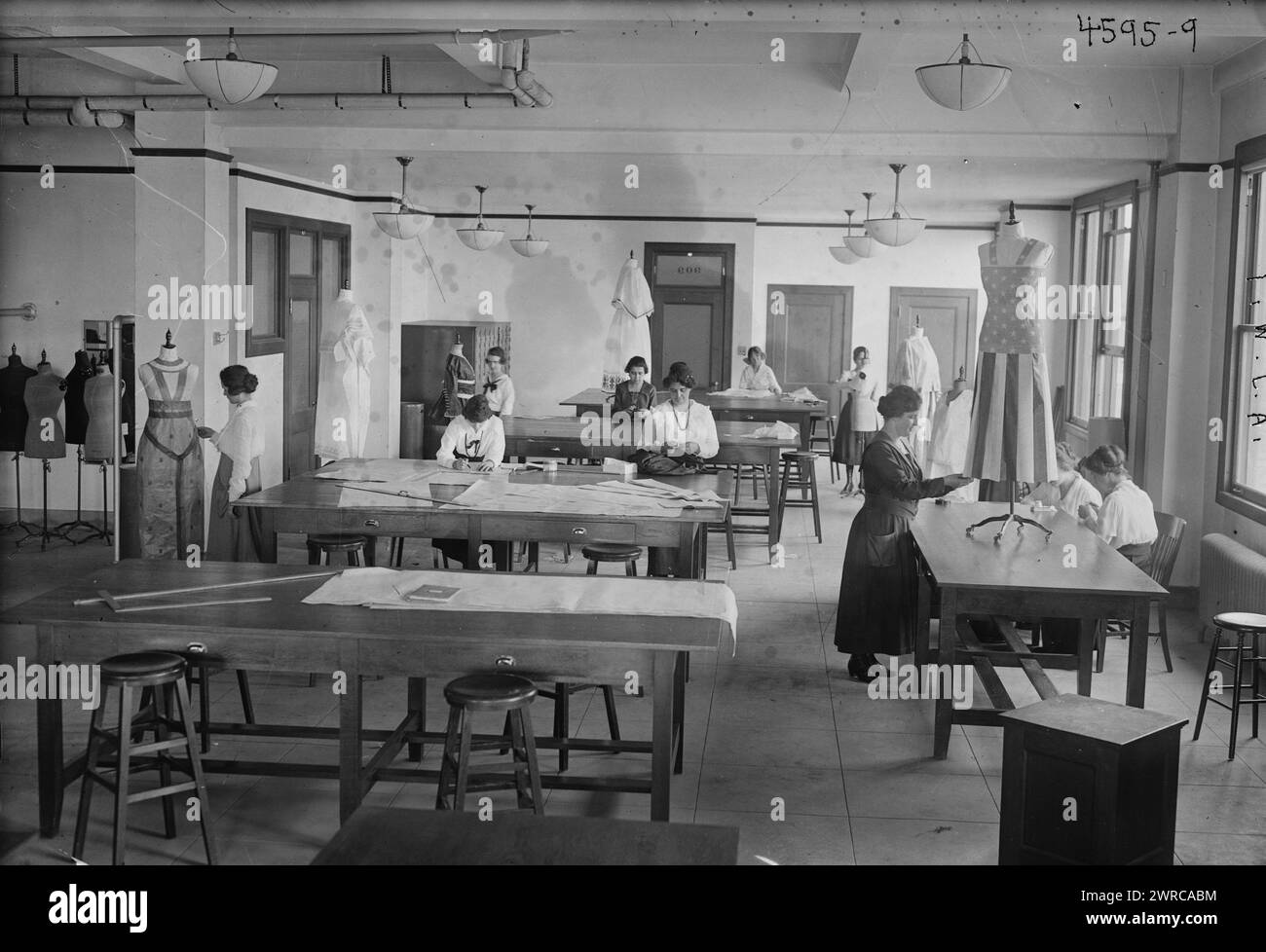 Y.W.C.A., Photograph shows women making dresses at the Y.W.C.A during World War I. One dress has a striped skirt and star-patterned top which resembles an American flag., between ca. 1915 and 1918, World War, 1914-1918, Glass negatives, 1 negative: glass Stock Photo