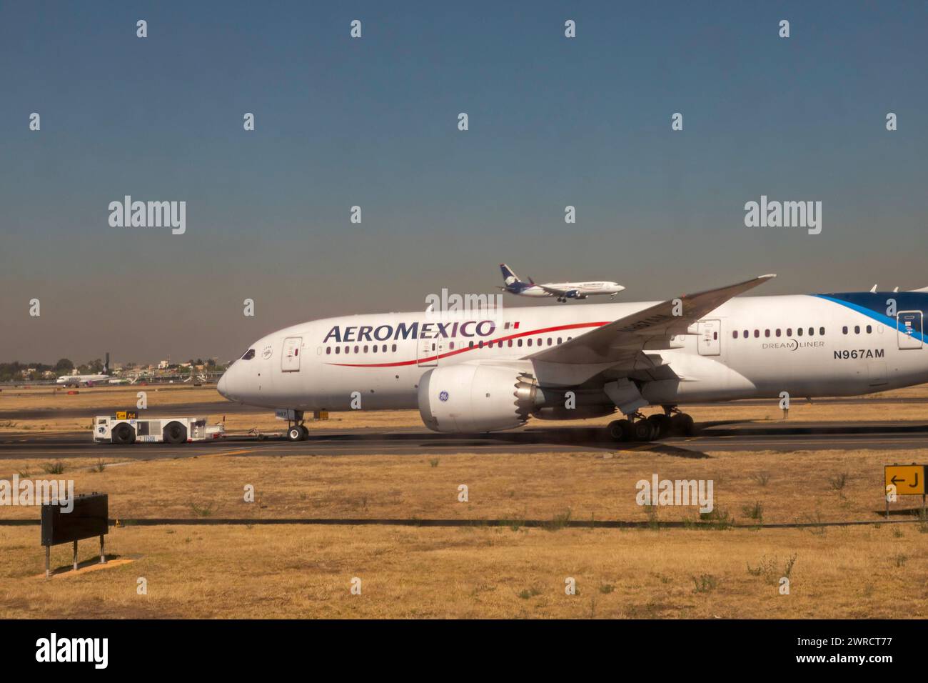 Mexico City - An AeroMexico Boeing 787-8 Dreamliner sits on the tarmac while another AeroMexico flight lands on a nearby runway. Stock Photo