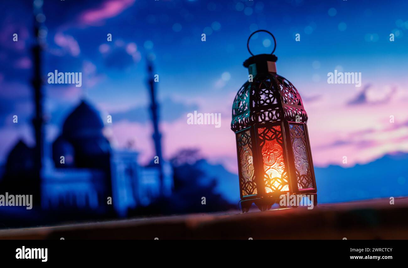 Ornamental Arabic lantern with burning candle glowing at night background. Festive greeting card, invitation for Muslim holy month Ramadan Kareem. Stock Photo