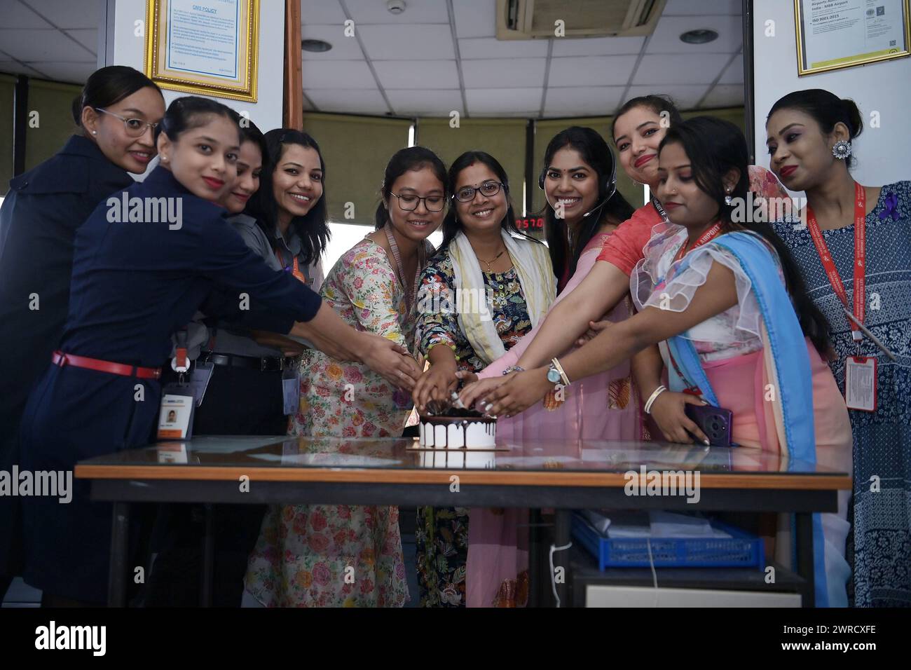 Air traffic controllers, air hostesses, and cabin crew are cutting cake to celebrate International Women's Day at Agartala airport's ATCT Tower in Tripura, India. Stock Photo