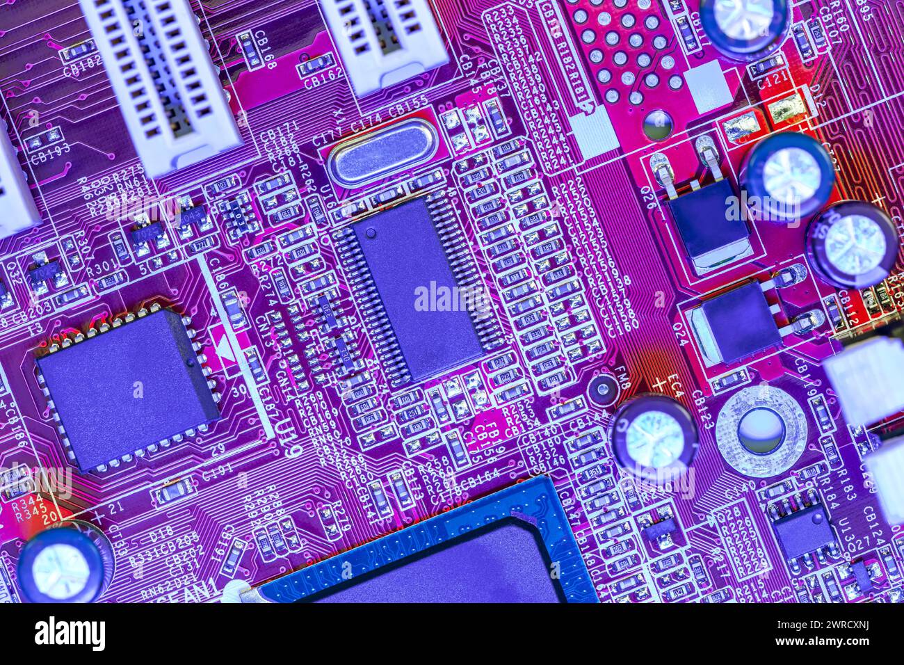 printed circuit board with different electrical components in colored illumination. Stock Photo