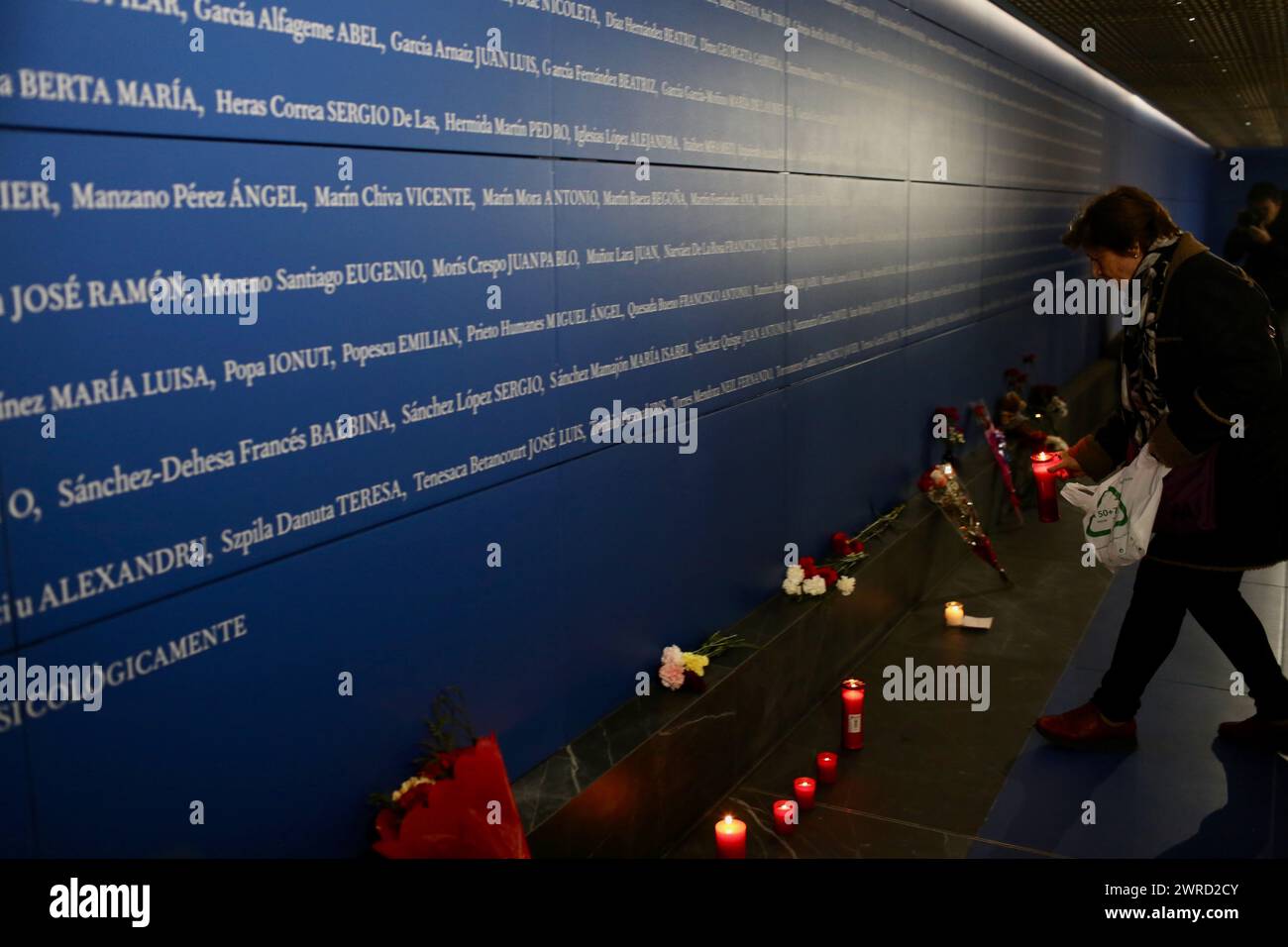 Madrid, Spain. 11th Mar, 2024. A woman places a candle in front of a plaque with the names of the victims of the bomb attack at Atocha station. The Islamist train attacks in Madrid on the morning of March 11, 2004, which left more than 190 dead and around 2000 injured, involved a series of simultaneous bomb attacks on a commuter train. Credit: Cesar Luis de Luca/dpa/Alamy Live News Stock Photo