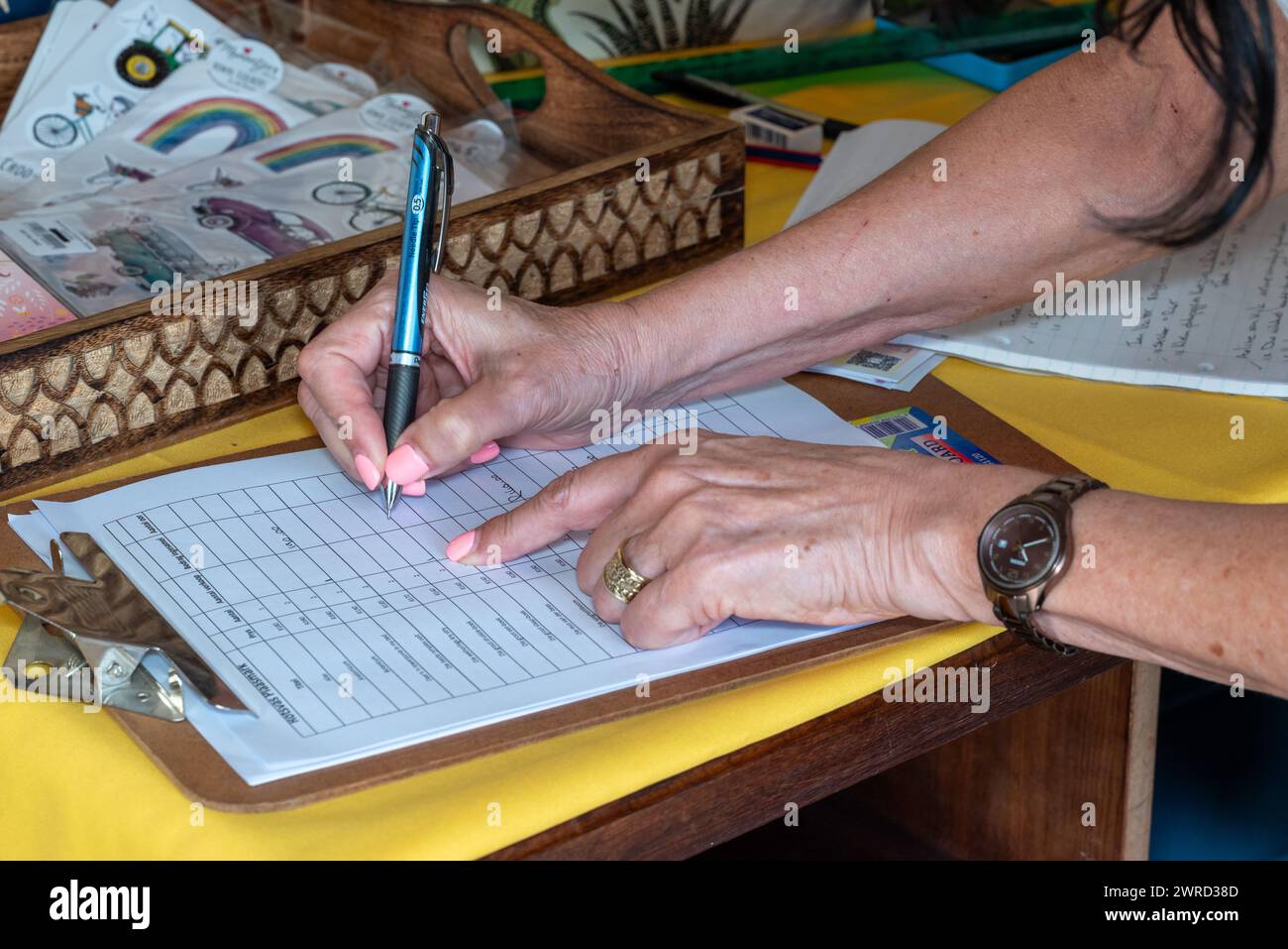 A woman's hands writing in a list on a clipboard Stock Photo