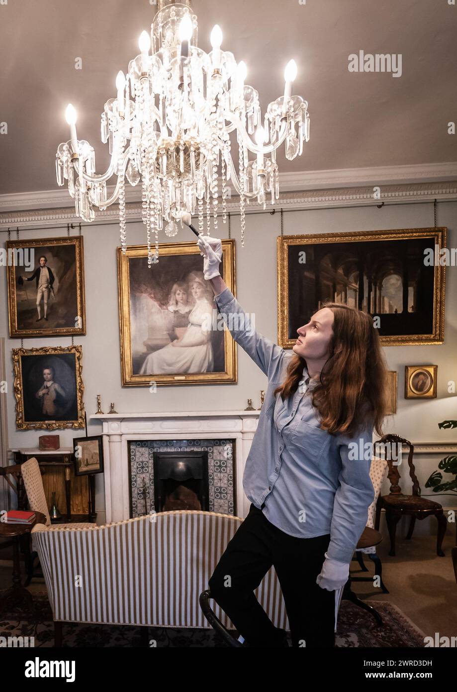 Conservation Intern Sally Brooker cleans a chandelier at Kiplin Hall and Gardens as the the historic house has reopened for their 2024 season. Built in the 1620s for George Calvert - founder of Maryland, USA - visitors to Kiplin Hall will be able to encounter 400 years worth of history lived out by members of the four families that owned Kiplin Hall over the centuries. Picture date: Monday March 11, 2024. Stock Photo