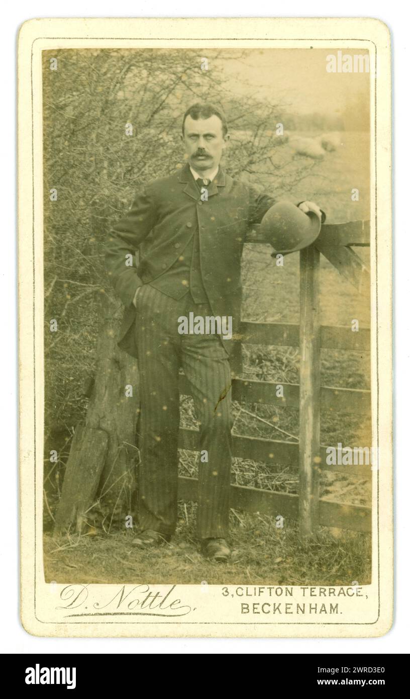 Original Victorian Carte de Visite (visiting card or CDV) handsome gent, in a suit holding a bowler hat, photographed in a rural setting, by field of sheep by D. Nottle of 3 Clifton Terrace, Beckenham, Kent, U.K. Circa 1880's Stock Photo