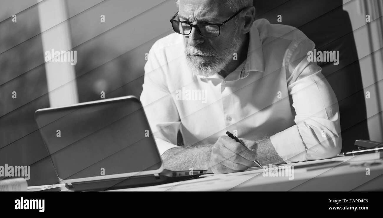 Senior businessman taking notes in office, hard light, geometric pattern Stock Photo