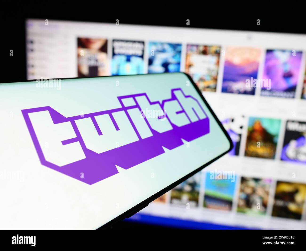 Cellphone with logo of American live streaming company Twitch Interactive Inc. in front of website. Focus on center-left of phone display. Stock Photo