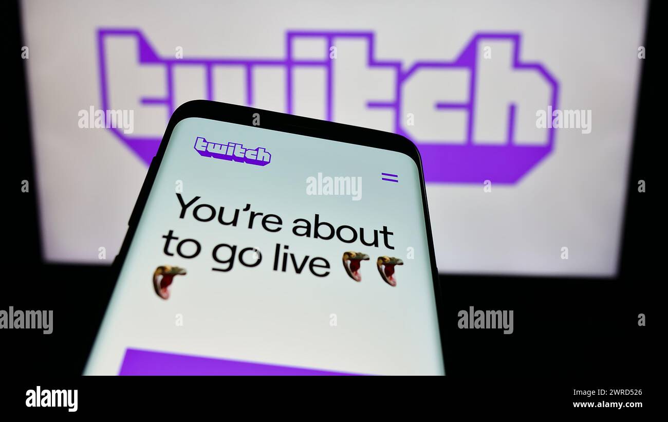 Mobile phone with website of US live streaming company Twitch Interactive Inc. in front of business logo. Focus on top-left of phone display. Stock Photo