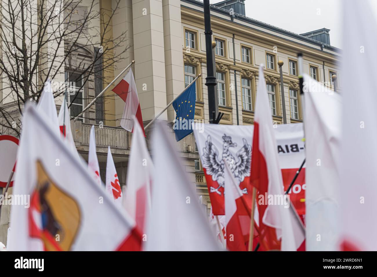 06.03.2024. Warsaw, Poland. polish flags waving at the protest, polish and EU flags hanging on a building in the background. High quality photo Stock Photo