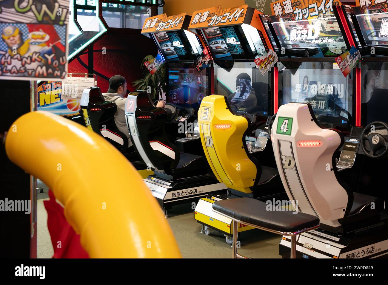 man playing racing car game at and arcade amusement game center. Stock Photo