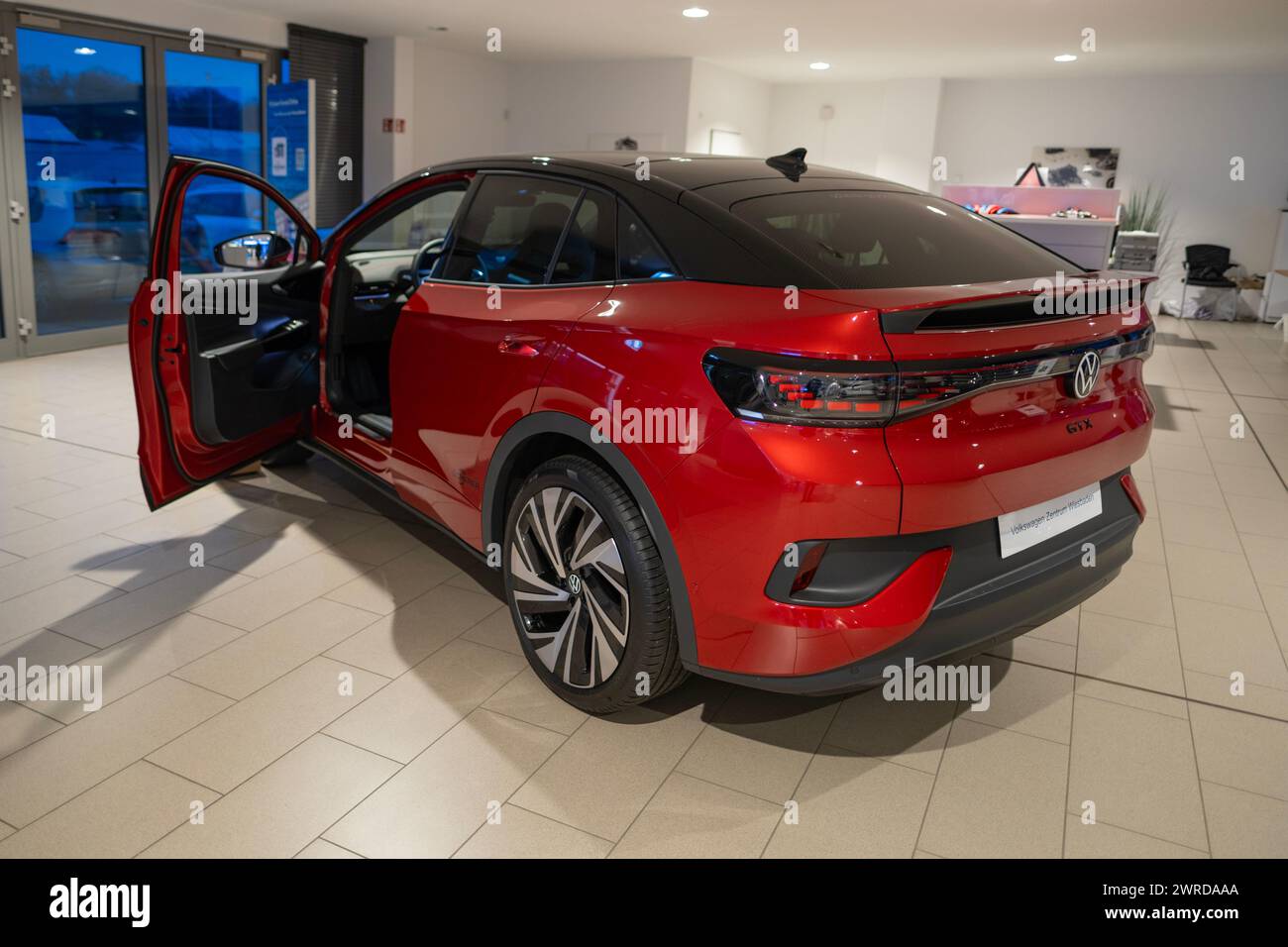 sleek Red Premium Metallic Volkswagen ID.5 GTX electric SUV parked in showroom with doors open revealing spacious and modern roomy suitable interior, Stock Photo