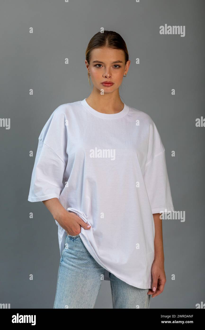 Beautiful blonde girl in a white oversized T-shirt and blue jeans ...