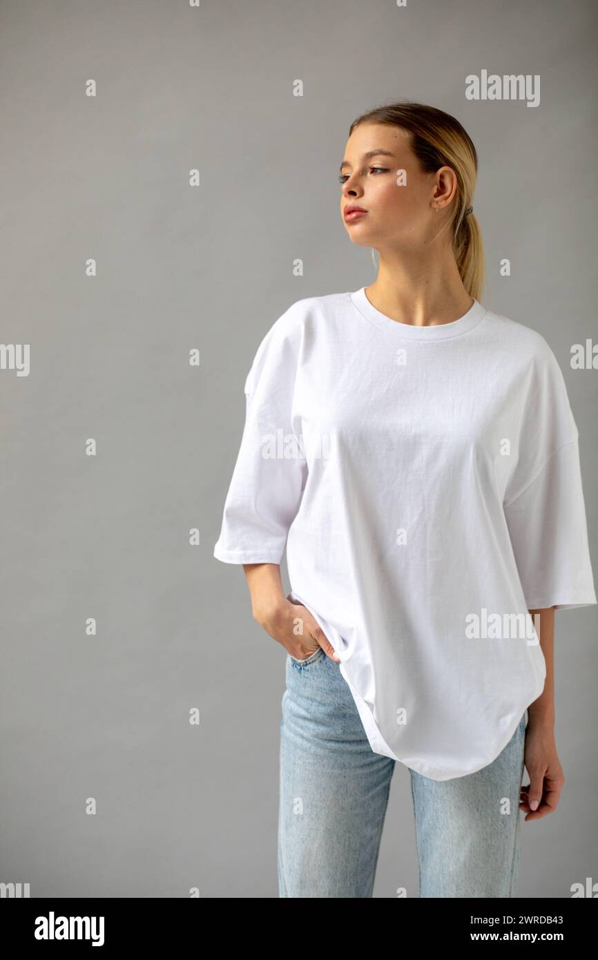 Beautiful blonde girl in a white oversized T-shirt and blue jeans ...