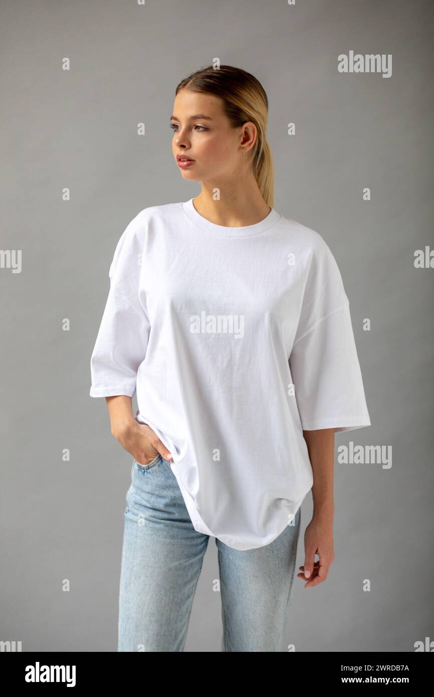 Beautiful blonde girl in a white oversized T-shirt and blue jeans ...