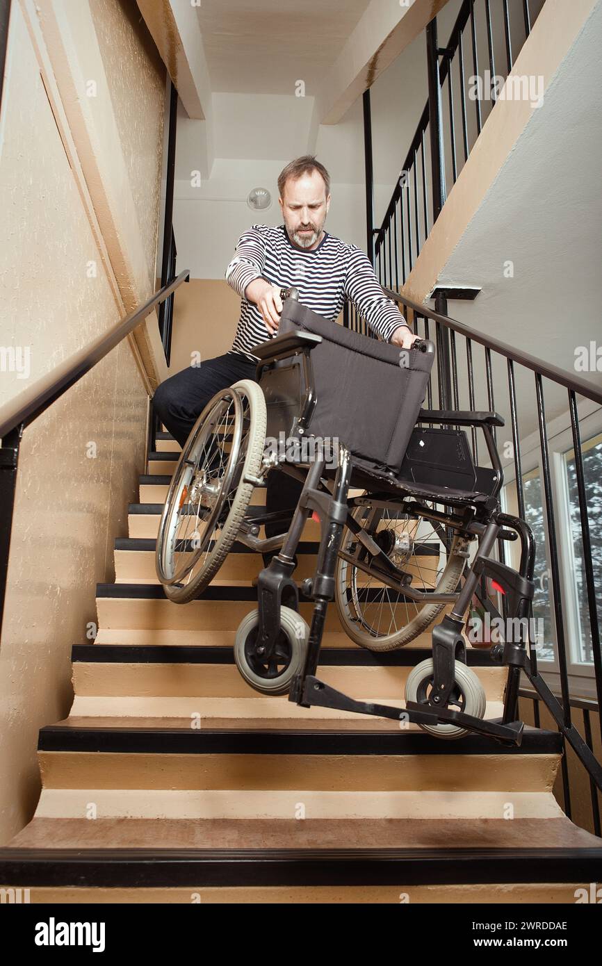 Man helping to move wheel chair downstairs in prefab house Stock Photo