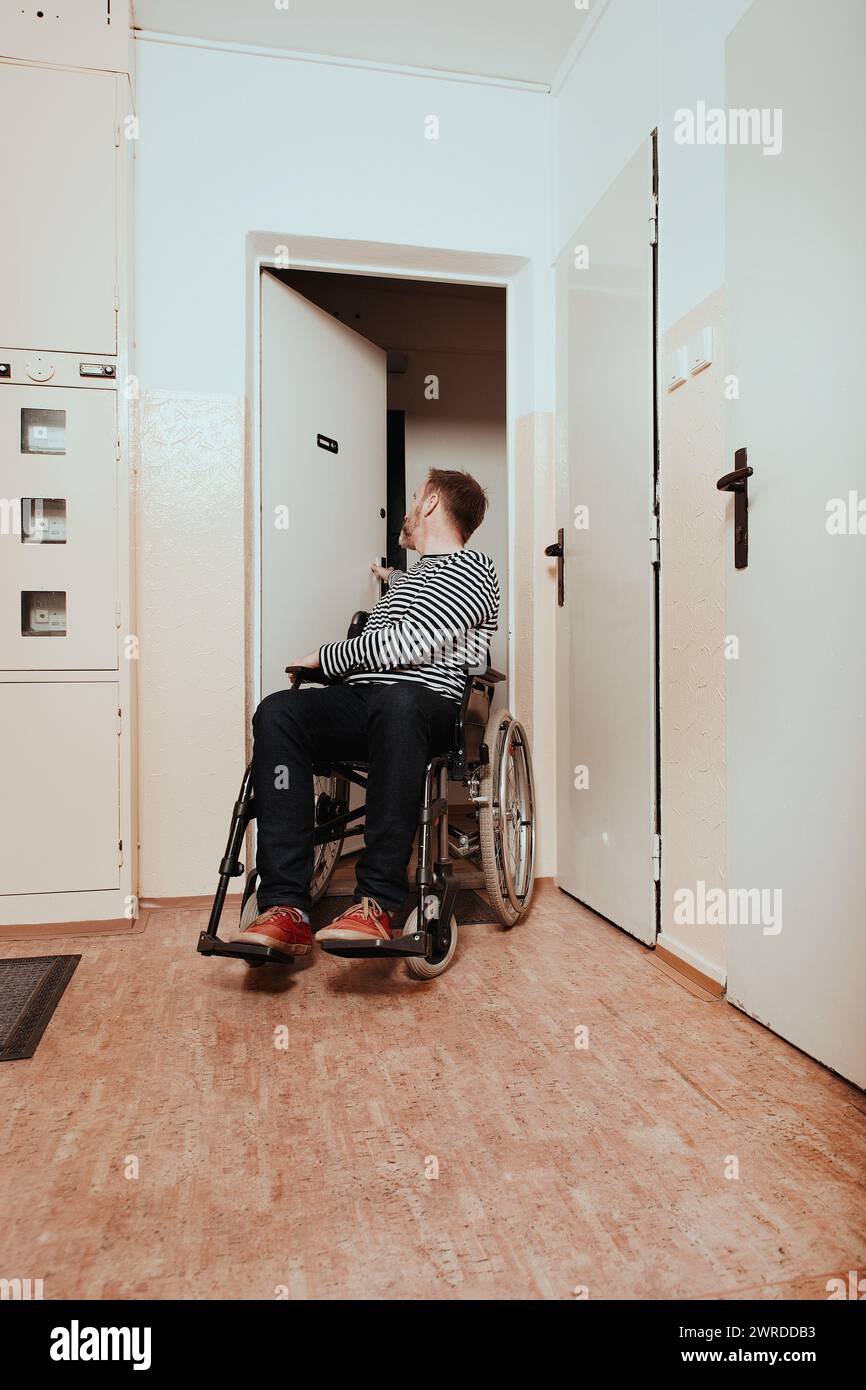 Disabled man on wheel chair leaving his apartment in prefab hous Stock Photo