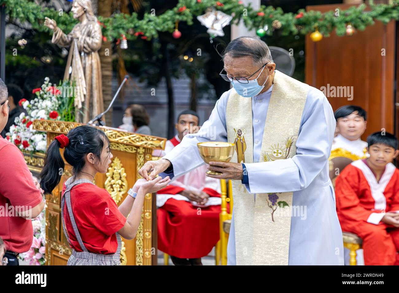 Priest giving communion to congregation during Christmas mass at St. Nikolaus Catholic Church, Pattaya, Thailand Stock Photo