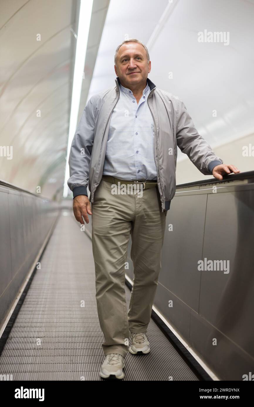 Middle aged man on moving walkway Stock Photo