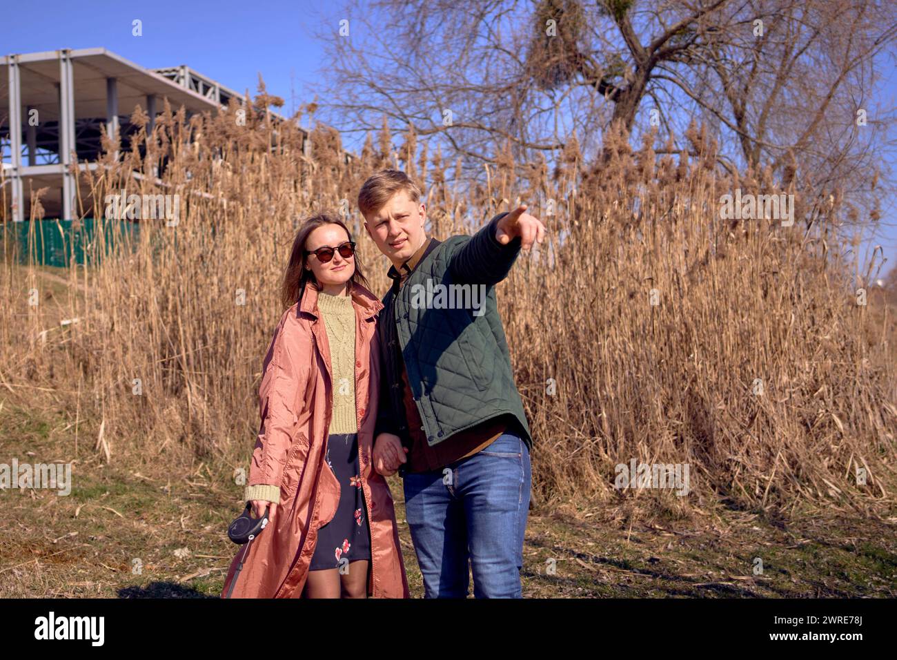 young stylish couple walking with their cockapoo dog near the river, an ...