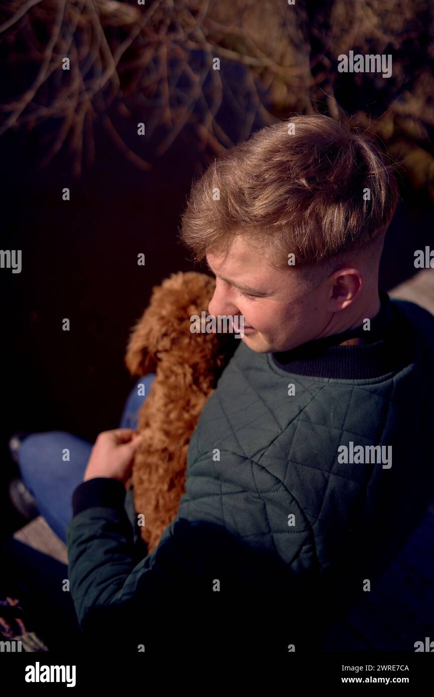 boy sits on a pier and hugs a cockapoo Stock Photo - Alamy