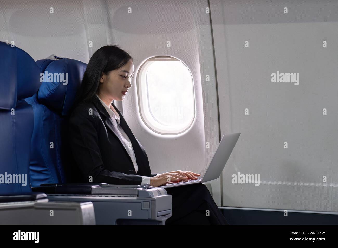 Asian young woman using laptop at first class on airplane during flight, Traveling and Business concept Stock Photo