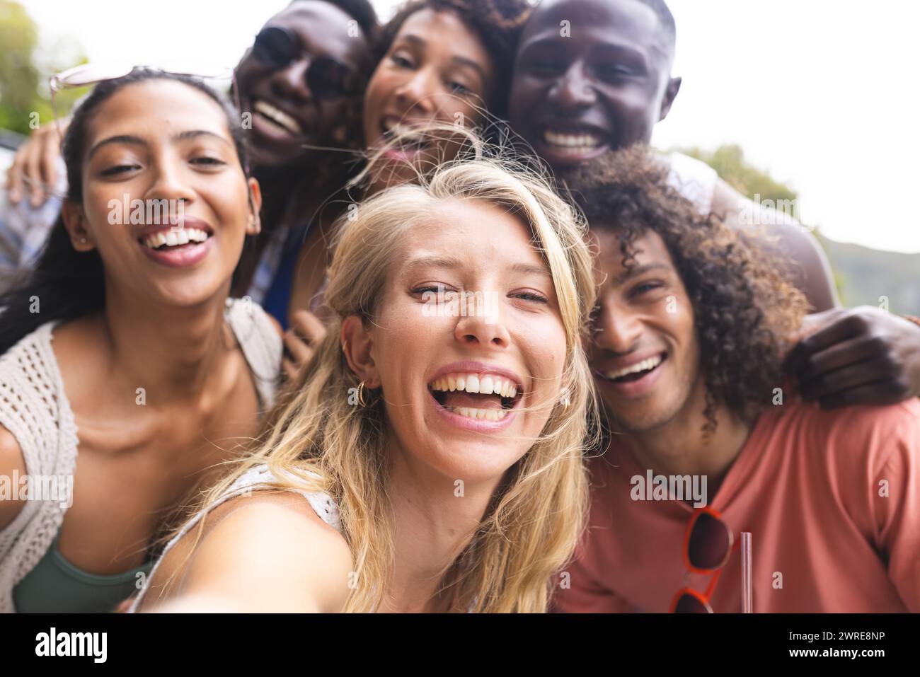 Diverse group of friends taking selfie, huddled close with wide smiles Stock Photo