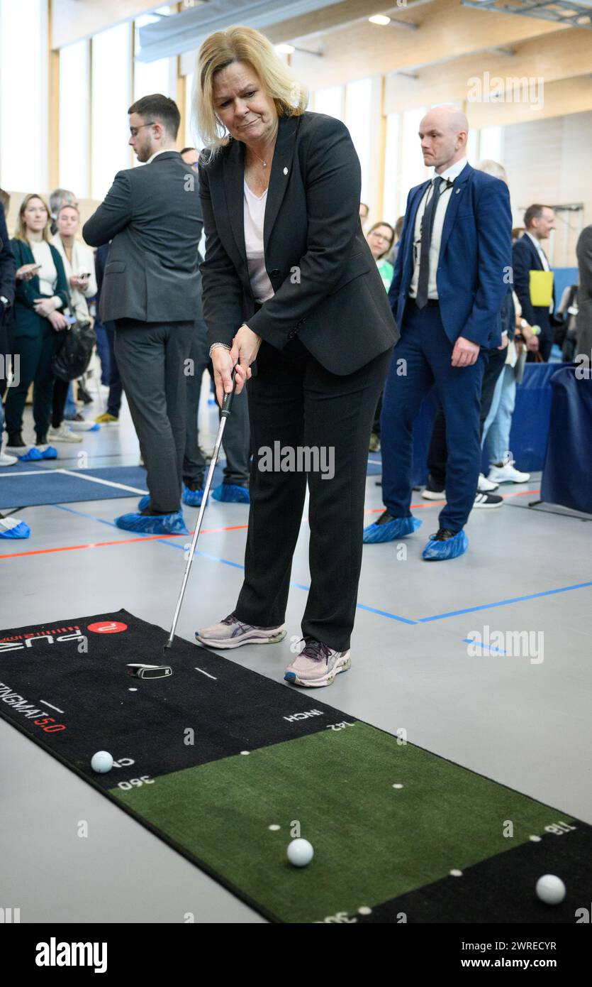 Berlin, Germany. 12th Mar, 2024. Nancy Faeser (SPD), Federal Minister of the Interior and Home Affairs, holds a golf club during a tour of a sports course at the second 'Movement Summit' in the sports hall of the sports school in Berlin's Olympic Park. The event, organized by the Federal Ministry of the Interior and Home Affairs and the Federal Ministry of Health, focuses on the question of how sport and exercise can be promoted and the political and social framework conditions improved. Credit: Bernd von Jutrczenka/dpa/Alamy Live News Stock Photo