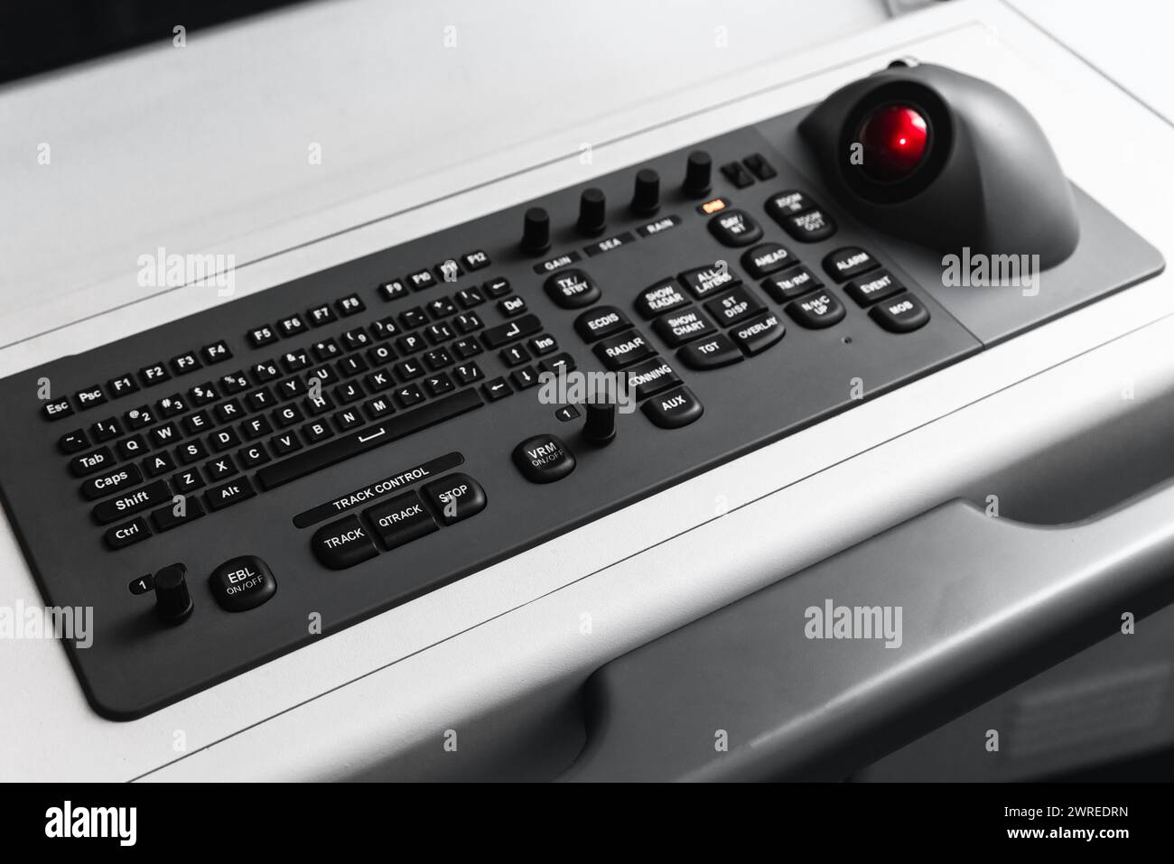 Built-in tabletop input device, black industrial keyboard with a trackball mouse, modern navigation equipment mounted on a control panel at captains b Stock Photo