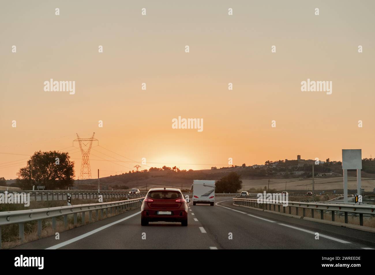 Vehicle on asphalt road, under sunset sky, driving on thoroughfare Stock Photo